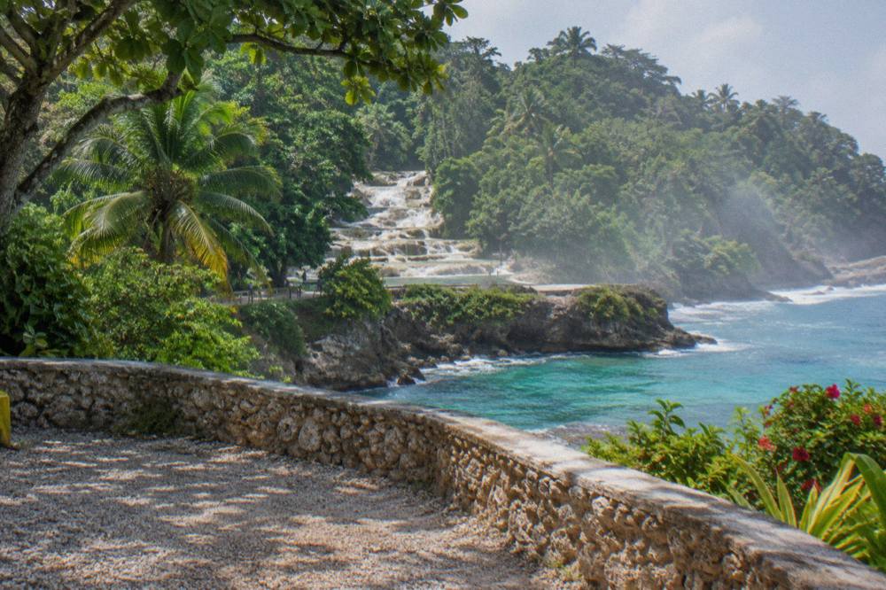 Tour vans parked on a coastal road above a turquoise bay in Ocho Rios